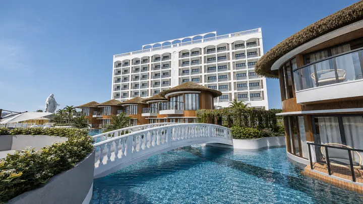 White arched footbridge crossing the pool between the villas
